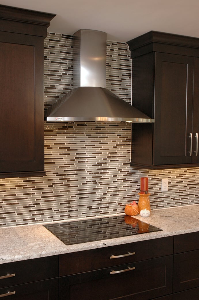 The stainless steel Chimney hood keeps with the sleek and contemporary design of this kitchen, and complements the dark finish of the cabinets.
