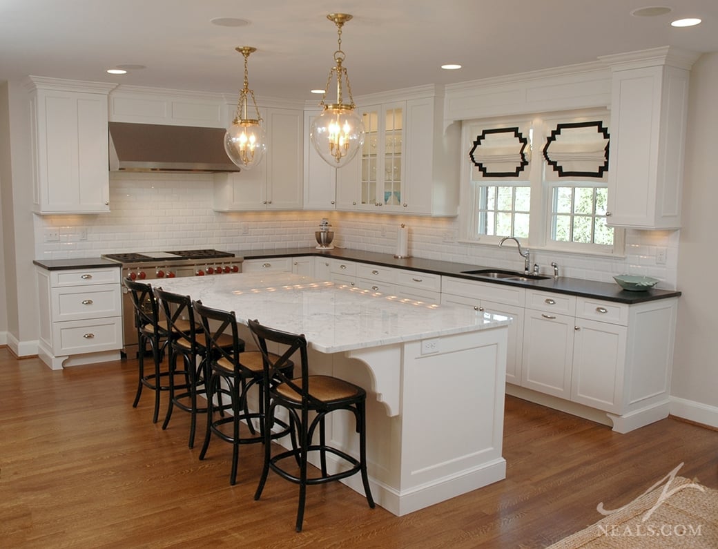 The use of dark countertops and bar seating ties together the white elements in this Neal's kitchen.