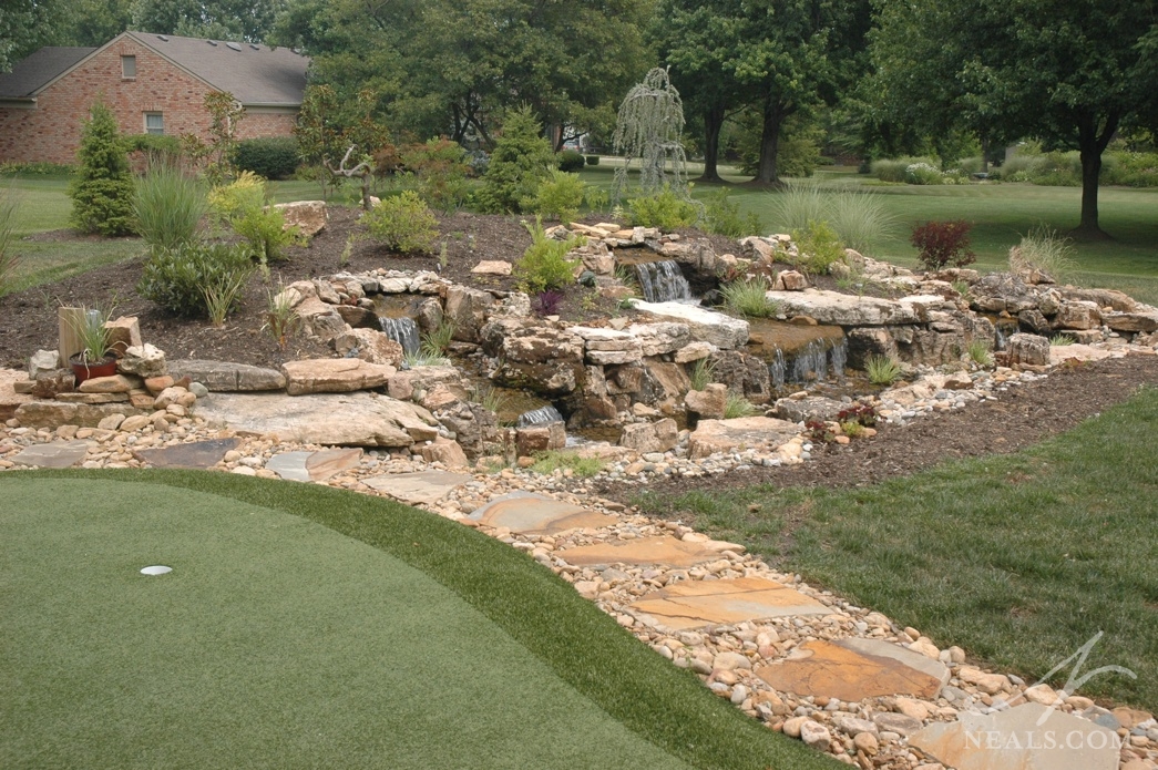 A long mound at the back of this yard is home to several small waterfalls that create a playfull creekbed-style feature. In addition to providing ambiance, the mound helps define the poperty's back boundary.