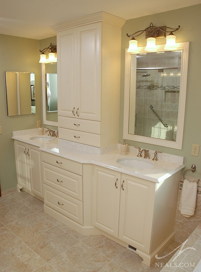 A storage cabinet tower on a double vanity. Brookhaven by Woodmode raised panel cabinetry in antique white.
