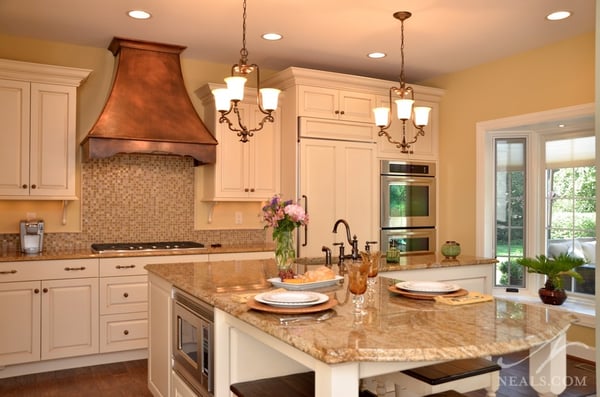 This French country kitchen design uses knobs, drawer pulls and a large pull for the fridge, all using stylish scroll-work or curve details.