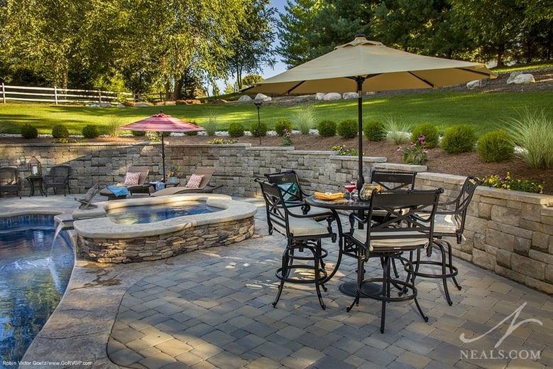 A long retaining wall holds the hillside back from this excavated area, where a large patio now welcomes guests.