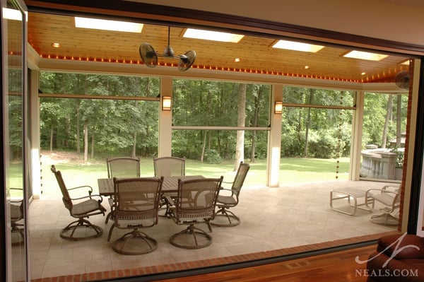 Glass panel doors fold open to create a large opening to the back porch. Motorized screens can be raised or lowered depending on the party's needs.