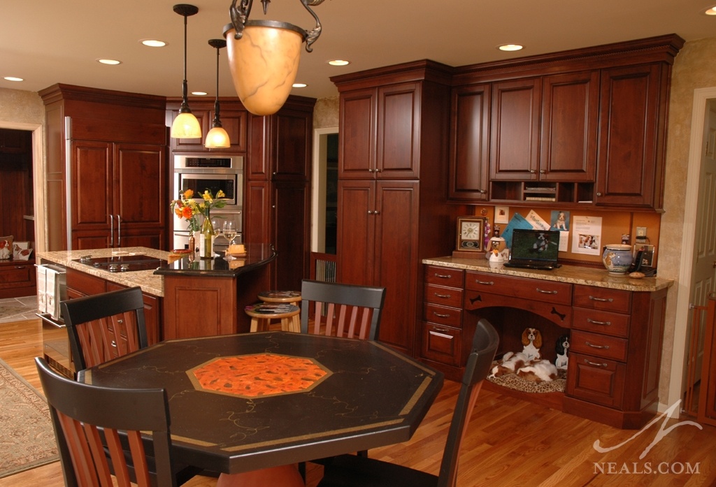 A counter in this kitchen remodel is accompanied by a cork board, small cubbies for paper and mail storage, and plenty of drawers to create a convenient communication center over the family dogs' bed.