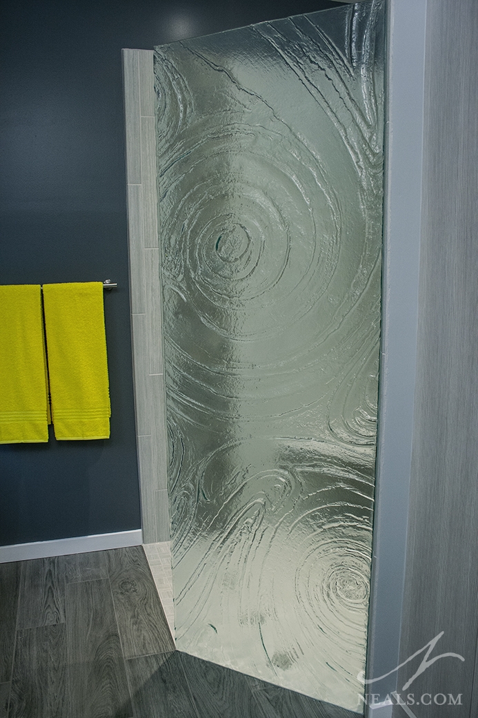 A vortex pattern using clear storm glass was used to create this custom walk-in shower partition.