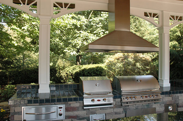 outdoor kitchen with stainless steel grills and hood