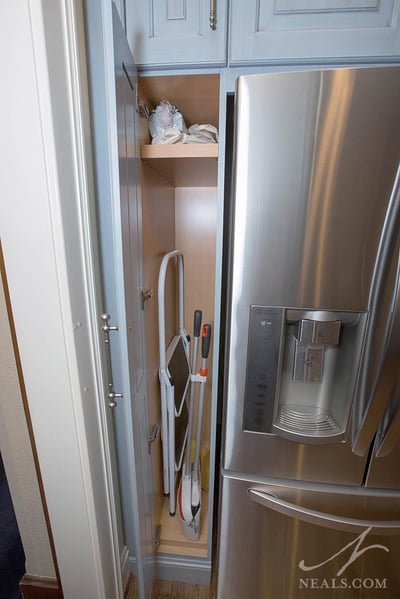 narrow broom closet next to fridge