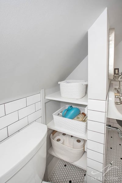 A niche in a bathroom filled with shelving for storage