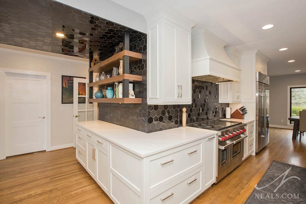 The ceramic tile backplash of black and gray hexagons transitions around the corner to include black leather tiles with a stone-like finish