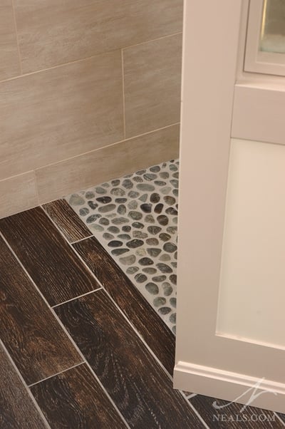 The two types of tile are matched at a threshold to create a level entryway from the bathroom into the shower.