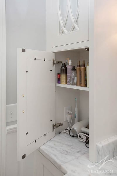 A cabinet on this Indian Hill bathroom vanity provides an outlet and space for daily personal care tools.