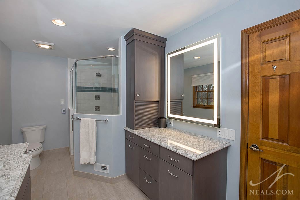 This bathroom in Fairfield uses a mirror with integrated lighting at the secondary vanity.