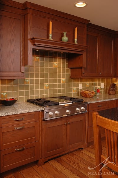 In this Neal's kitchen remodel, mossy green field tiles are paired with randomly placed painted tiles featuring a stylized ginkgo leaf design- a classic Craftsman motif.