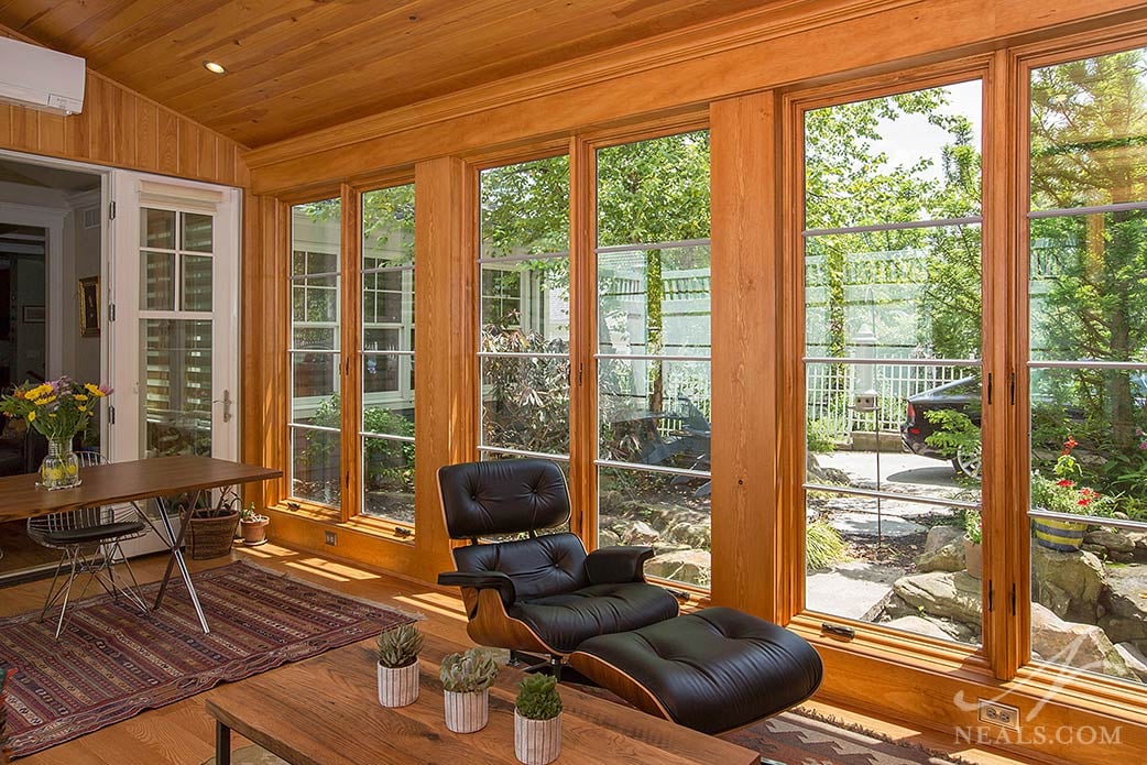 A sunroom in Madeira is a warm space with views to a well-appointed backyard garden.