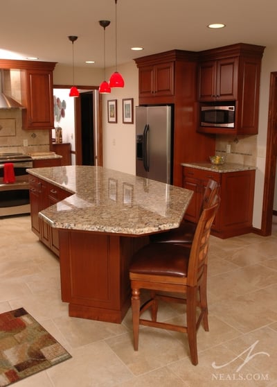Cream-colored, large format tiles compliment the warm wood and pale granite in this kitchen remodel.
